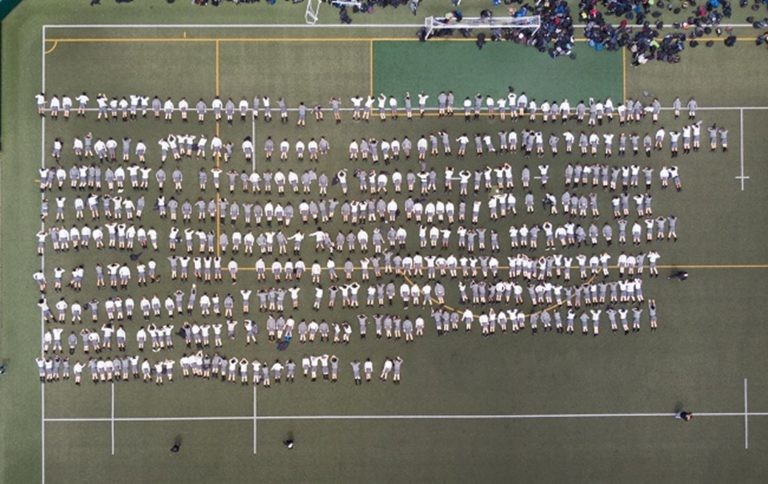 Photograph of 440 students at Wellington College lying on a field