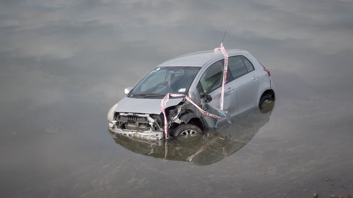 Damaged car half submerged in water