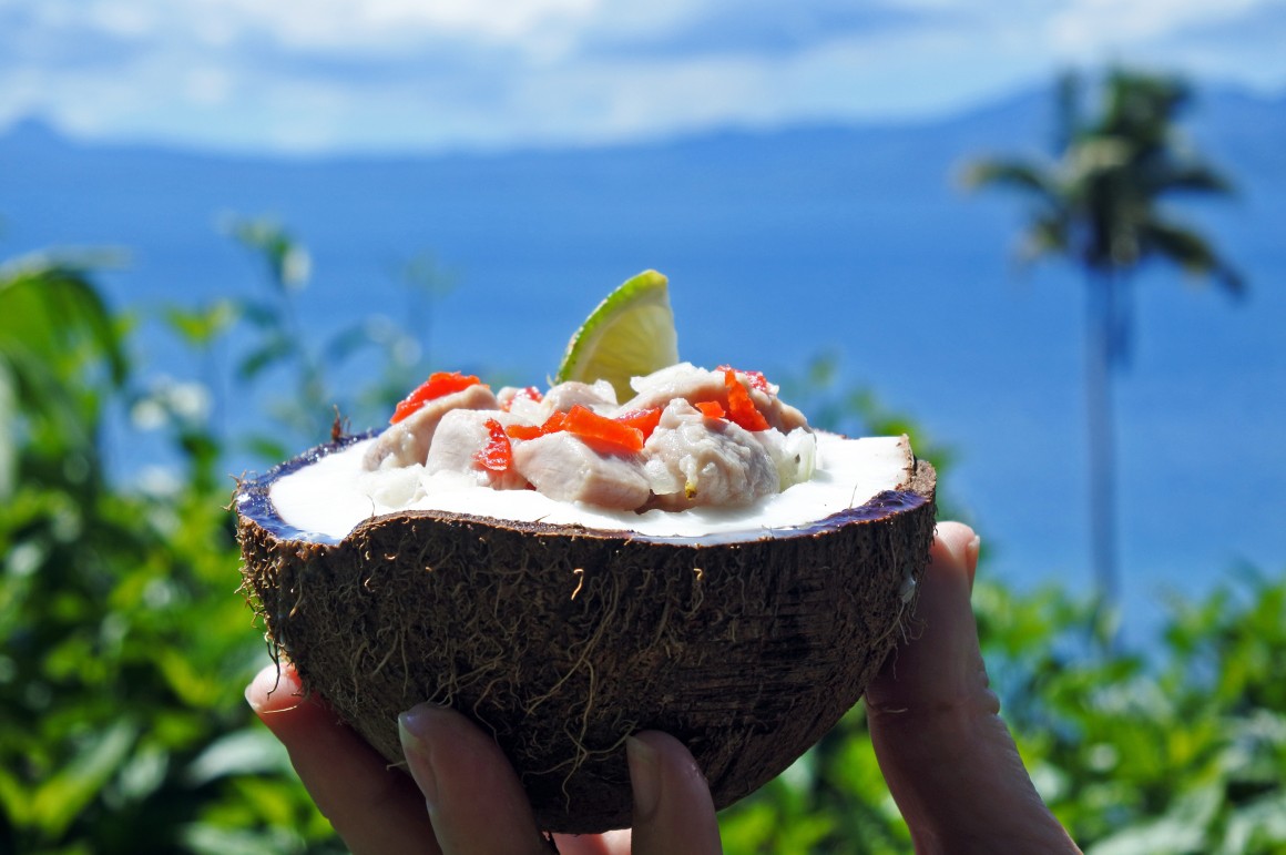 Hand holding fish curry in coconut