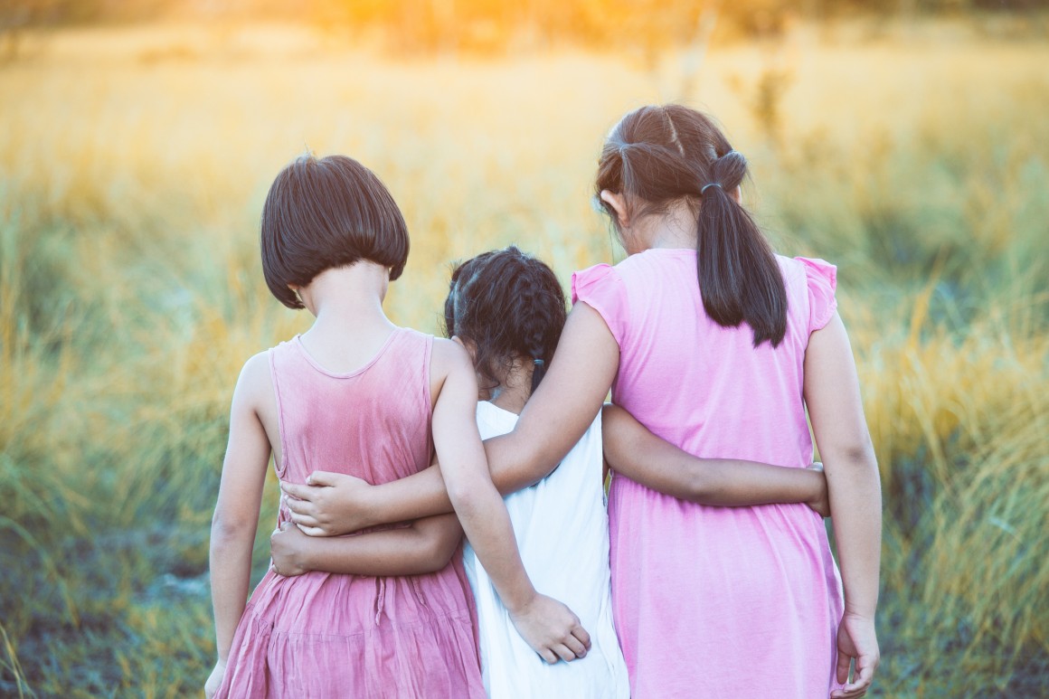 Rear view of three children in field