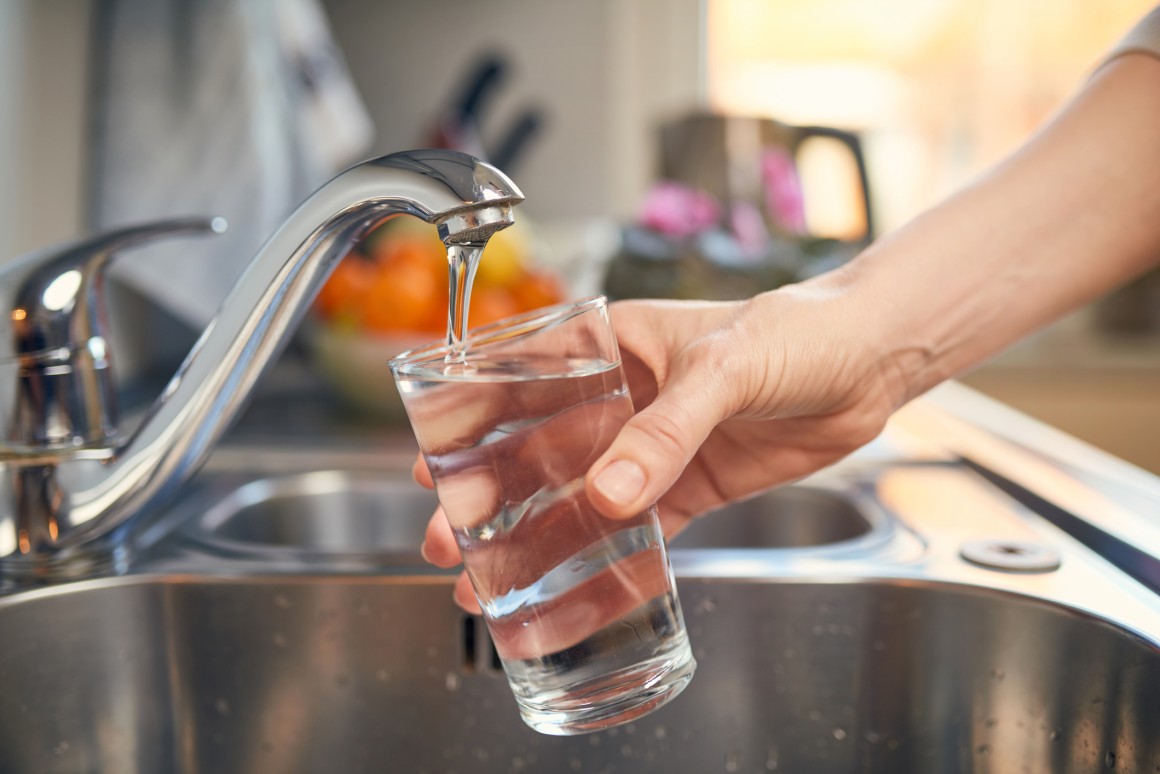 Filling up a glass of water from a tap in a kitchen