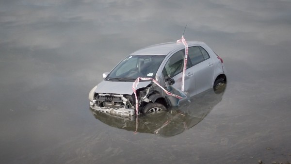 Damaged car half submerged in water