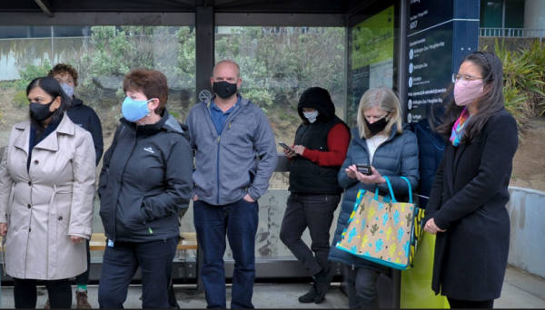 people masked at a bus stop 