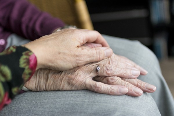Young hand comforting older person's hand
