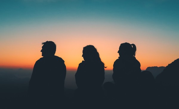 Three silhouettes of young people in sunset