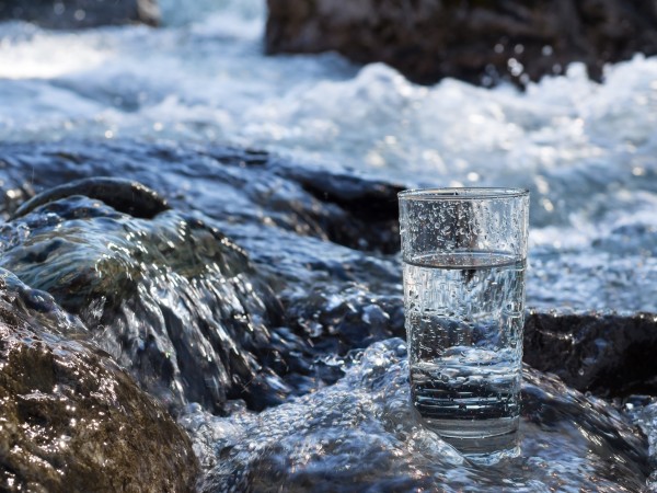 Glass of water in rushing stream