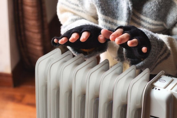 gloved hands held over radiator