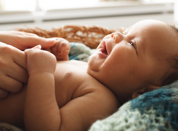 Smiling baby holding hands with mother