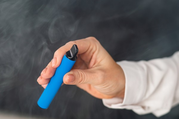 Hand holding blue disposable vape