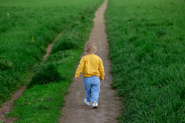 Child walking down a path through grass