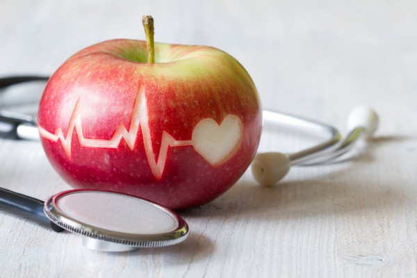 An apple with a heart figure and cardiogram superimposed