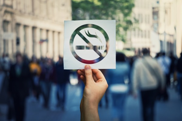 holding up a no smoke sign with blurred out crowd