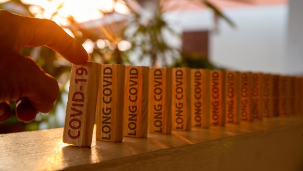 Standing wooden dominos with the words 'long covid' written on them 
