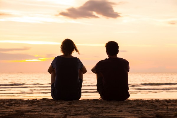 Silhouette of young people watching sunset on beach