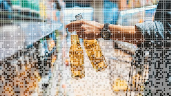 Image of hand taking beer bottles off shelf in store