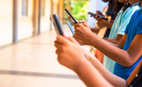 Young teens in a line on phones