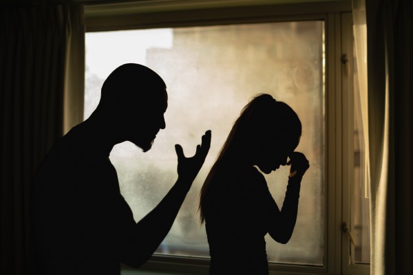 Man standing over woman in shadows