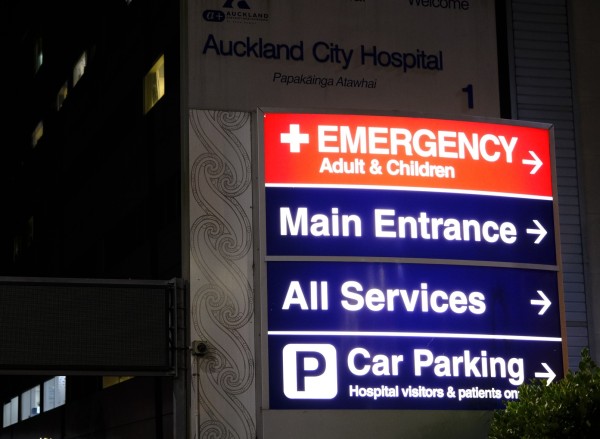 A lit up sign at night pointing to the Emergency department at Auckland Hospital.